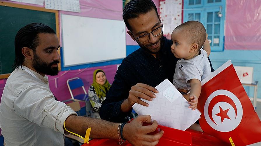 Baby in tow, a man in capital Tunis casts his ballot.
