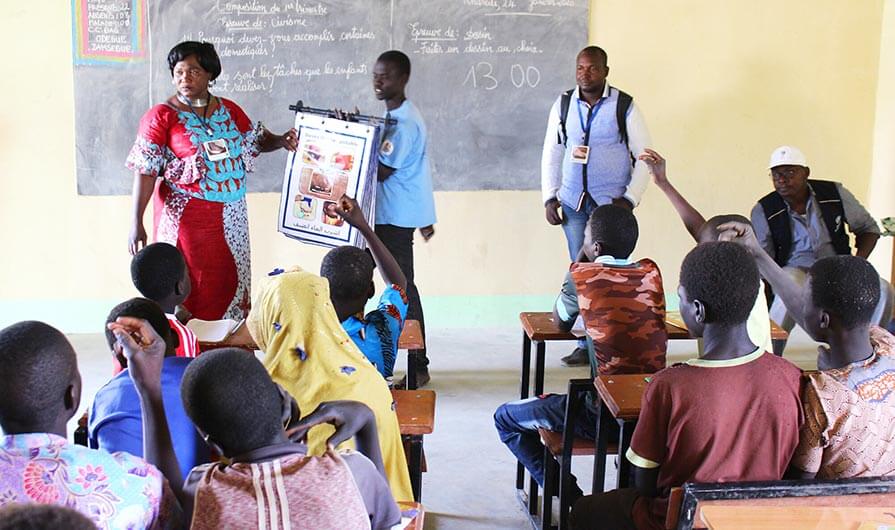 Health workers use flip charts to teach students in Chad about the Guinea worm life cycle.