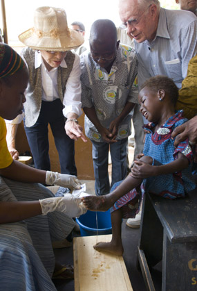Rosalynn Carter watches as a health worker dresses a child's Guinea worm wound.