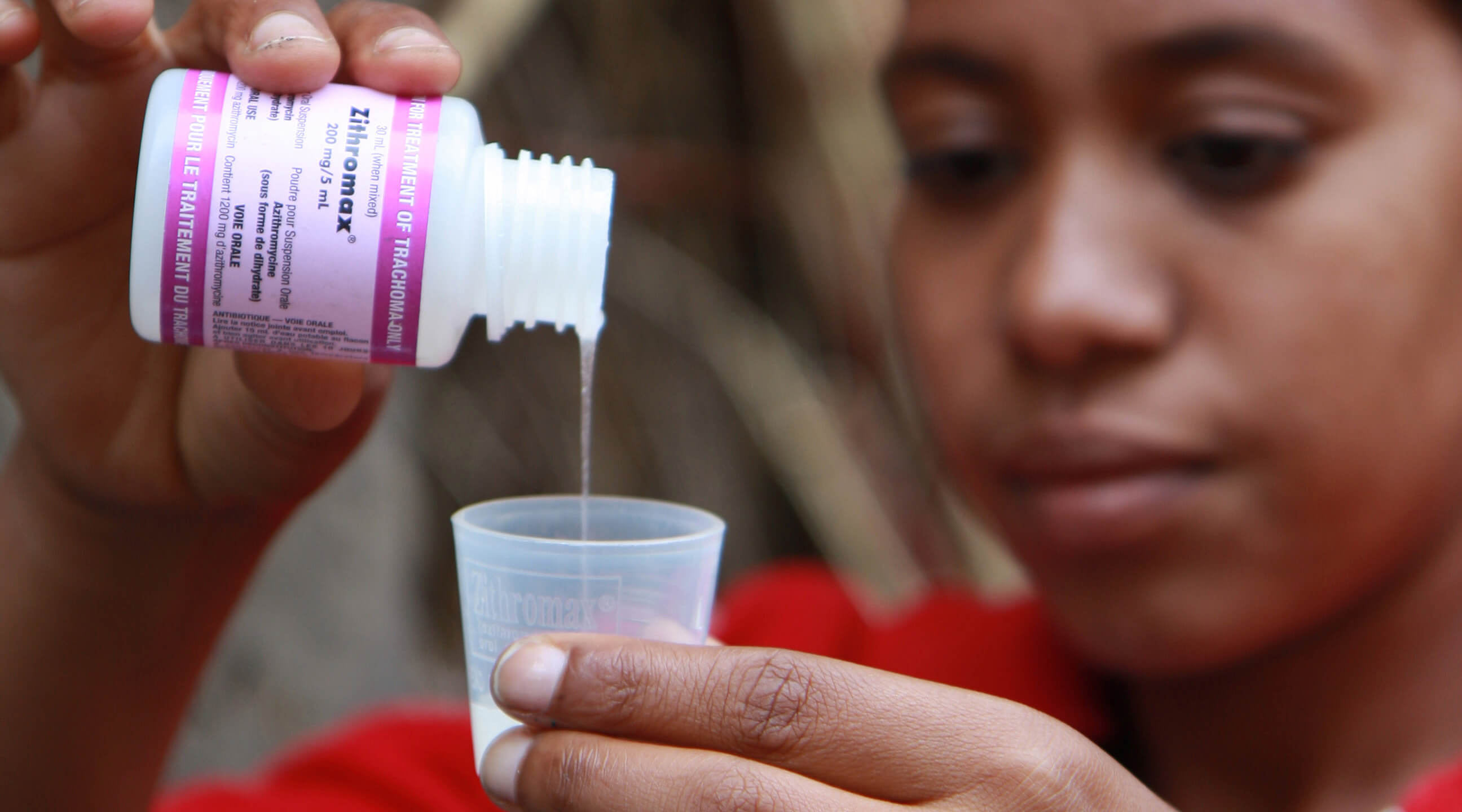 A health worker in Ethiopia pours a dose of the antibiotic syrup of Zithromax ® (azithromycin), which is used to treat the eye disease trachoma.