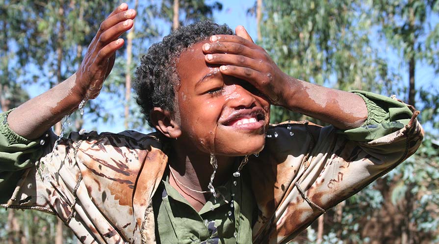 Close-up photo of a young child rinsing their face with water.
