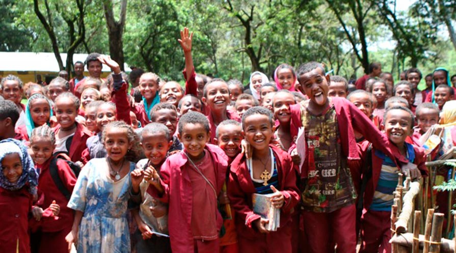 Group photo of children smiling and waving.
