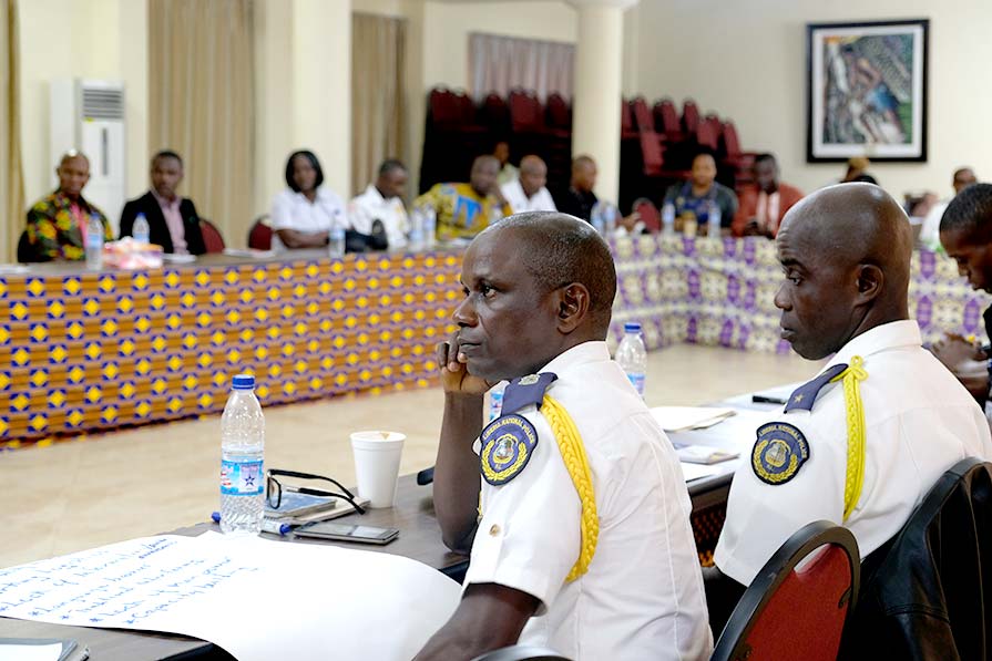 Photo of Liberia National Police members as they listen at a conference table.