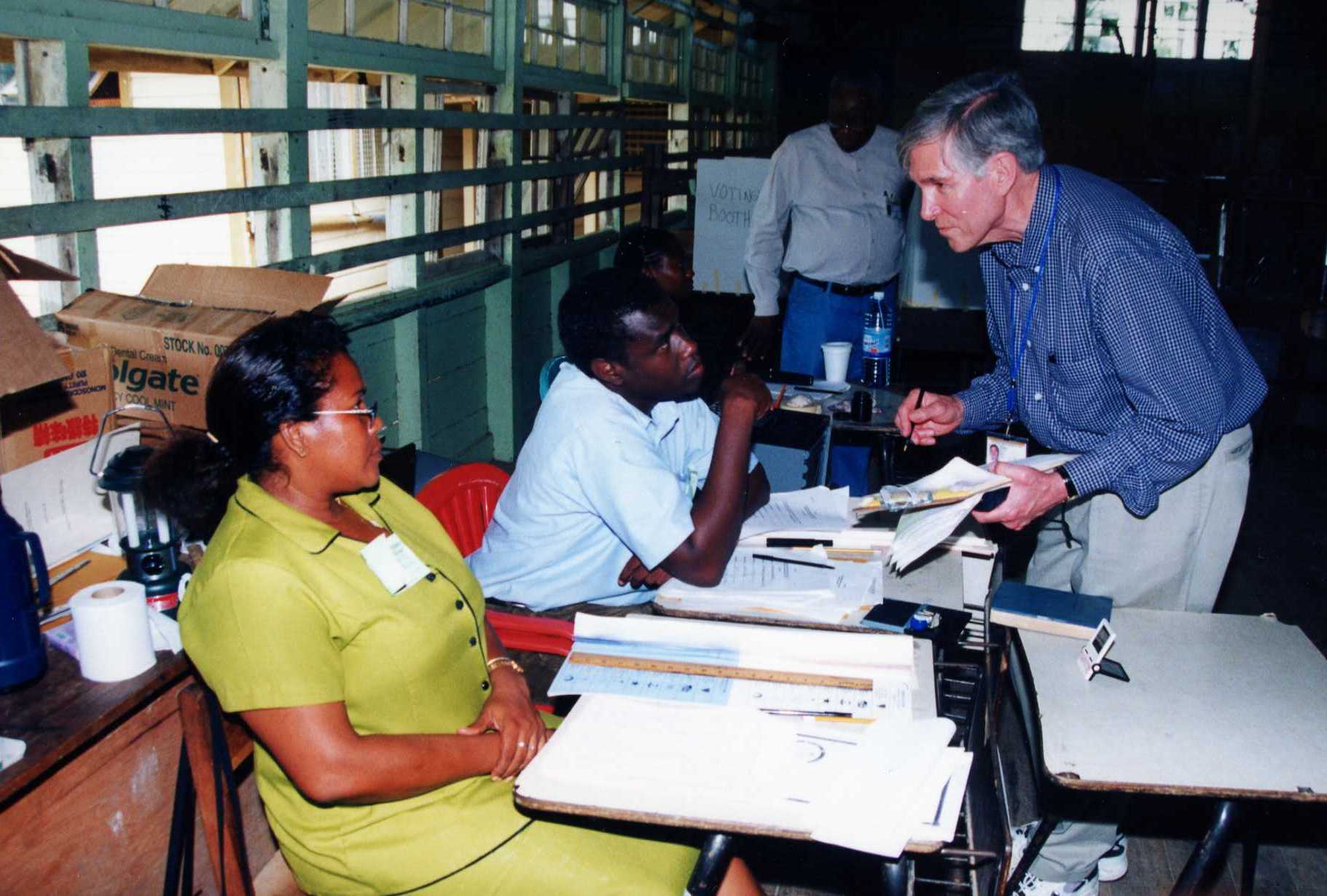 In this file photo, Dr. John Hardman talks to election workers as he observes polling in Guyana’s 2001 elections.