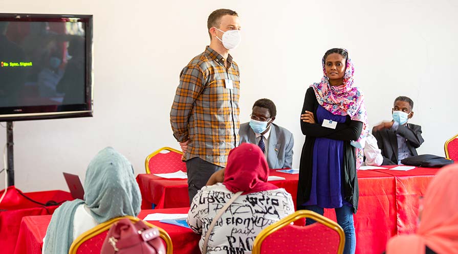 A man and woman are shown leading a workshop in Sudan.