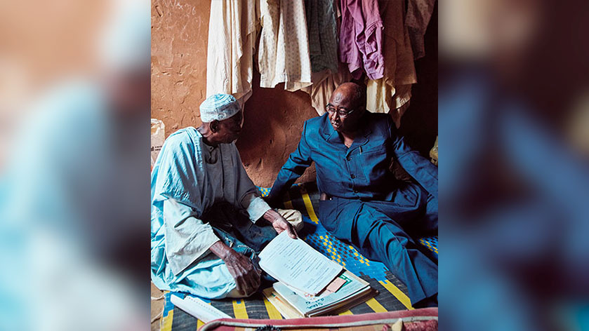 Kané (right) examines Guinea worm archives with Ousseini Mahamane, chief of Goulouské village in Zinder region and its former Guinea worm village volunteer.