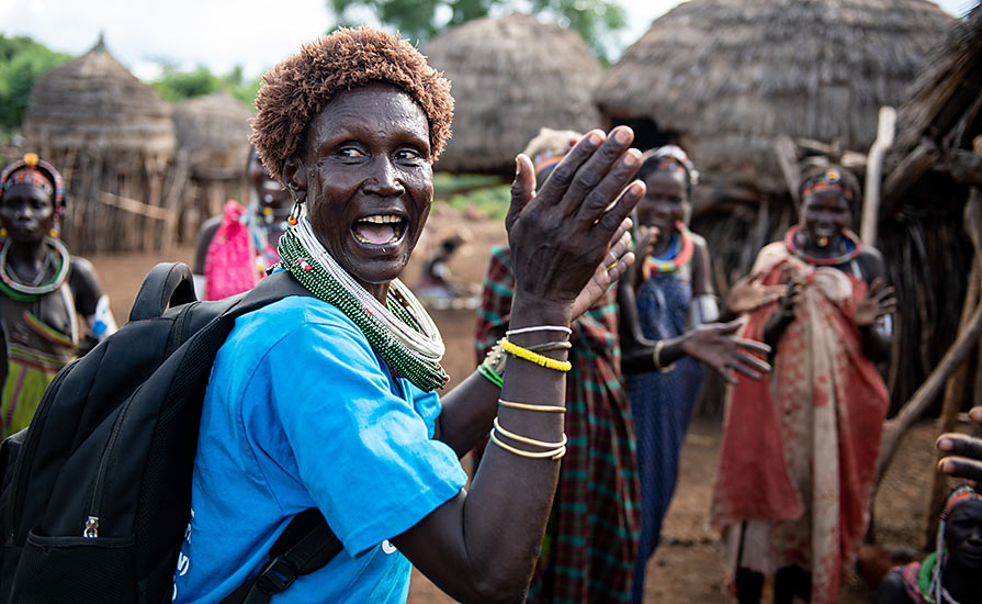 South Sudanese woman sings and claps her hands.