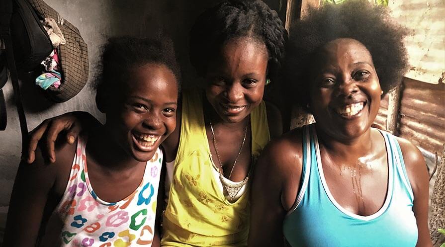 Antoinette Sainfabe (right) lives with her daughter and niece, as well as two sons, in her rebuilt home in Léogâne, Haiti. The house replaced the one that collapsed on top of Sainfabe during the 2010 earthquake.