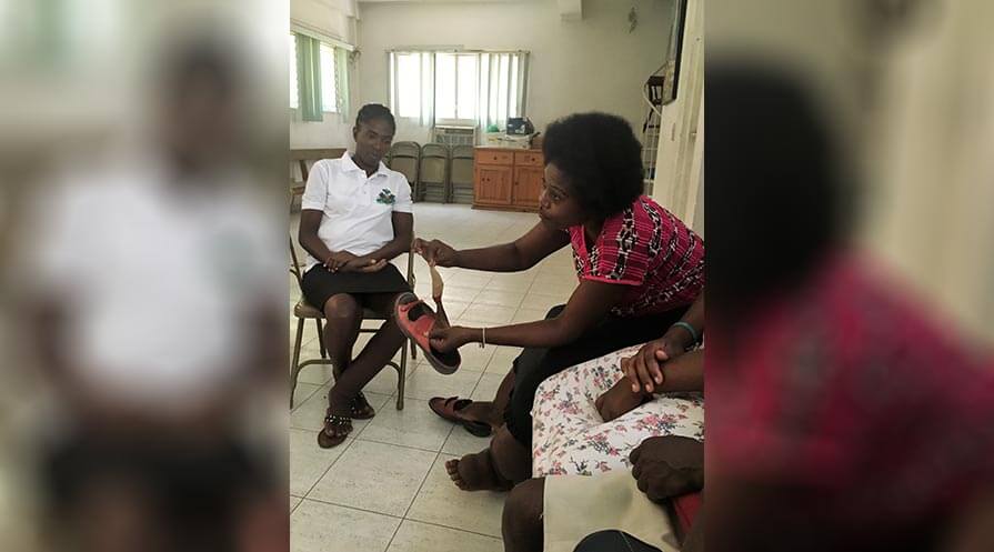 During a lymphatic filariasis Hope Group meeting at L’Hopital Ste Croix in Léogâne, Haiti, Antoinette Sainfabe shows how she has modified her shoe to accommodate her severely swollen foot.