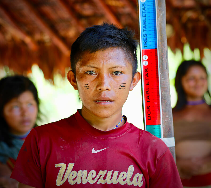 In Venezuela, a boy stands in front of a measuring tape to determine proper dosage of the medication that helps prevent river blindness, a parasitic eye disease. 