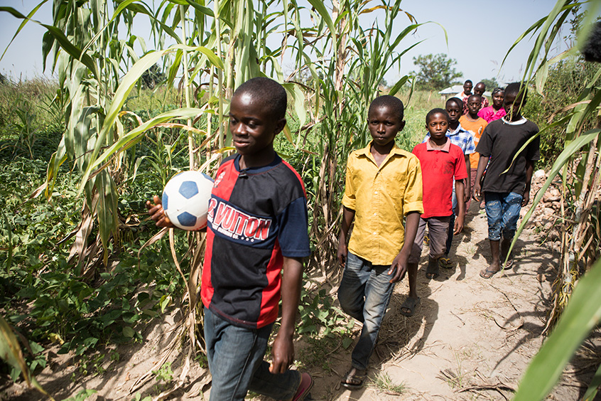 A boy in Nigeria walks with his soccer ball