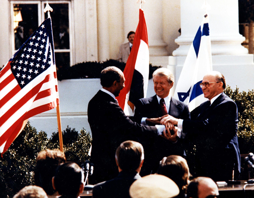 Egyptian President Anwar Sadat, U.S. President Jimmy Carter, and Israeli Prime Minister Menachem Begin make a three-way handshake at the signing of the Egyptian-Israeli Peace Treaty.