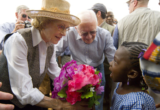 A young Nigerian girl presents former First Lady Rosalynn Carter with flowers.