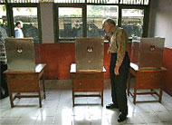 Former U.S. President Jimmy Carter examines a voting booth while poll workers finish setting up before voting begins in the July 5 Indonesia elections.