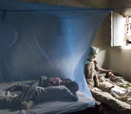 Photo of a bednet hung over a sleeping area and tucked under a mattress to protect sleepers from mosquitoes infected with malaria.
