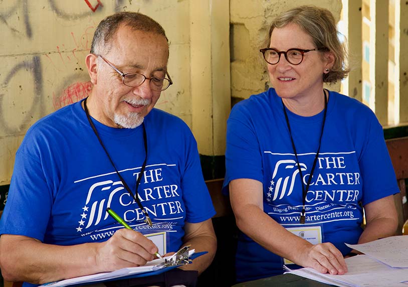 Two election observers wearing blue Carter Center tshirts.