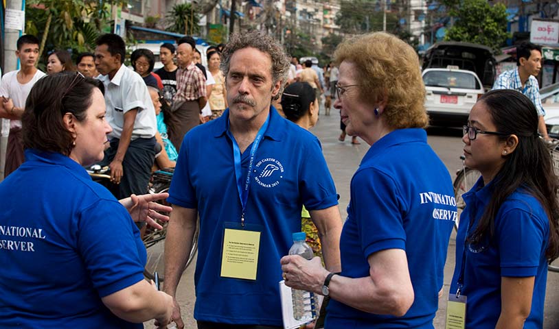 Photo of David Carroll with three observers, all in Carter Center branded blue t-shirts.