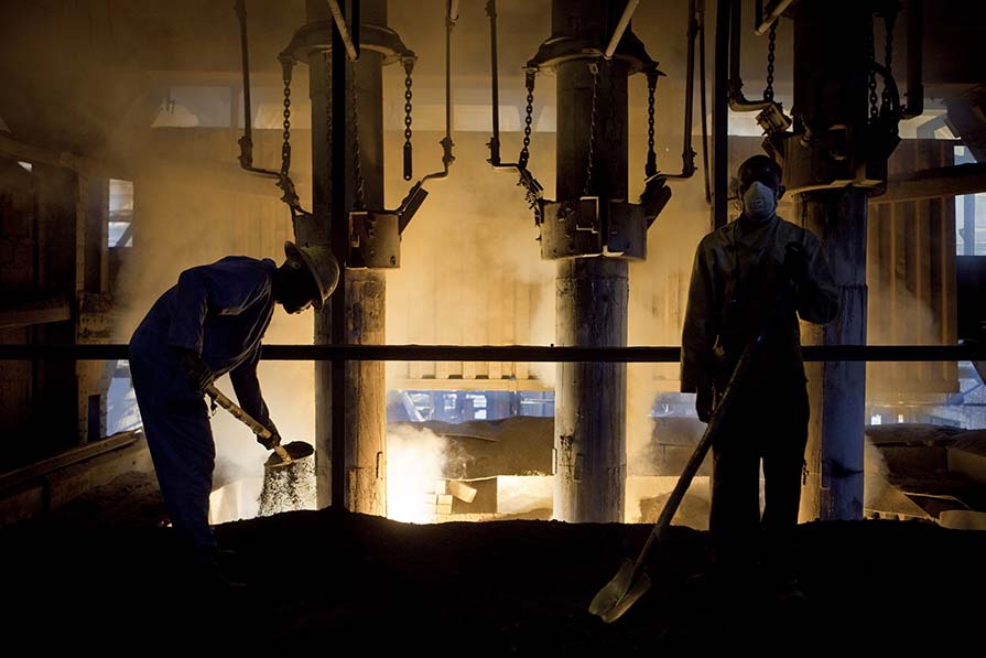 Backlit photo of two men working in a Congo mine.
